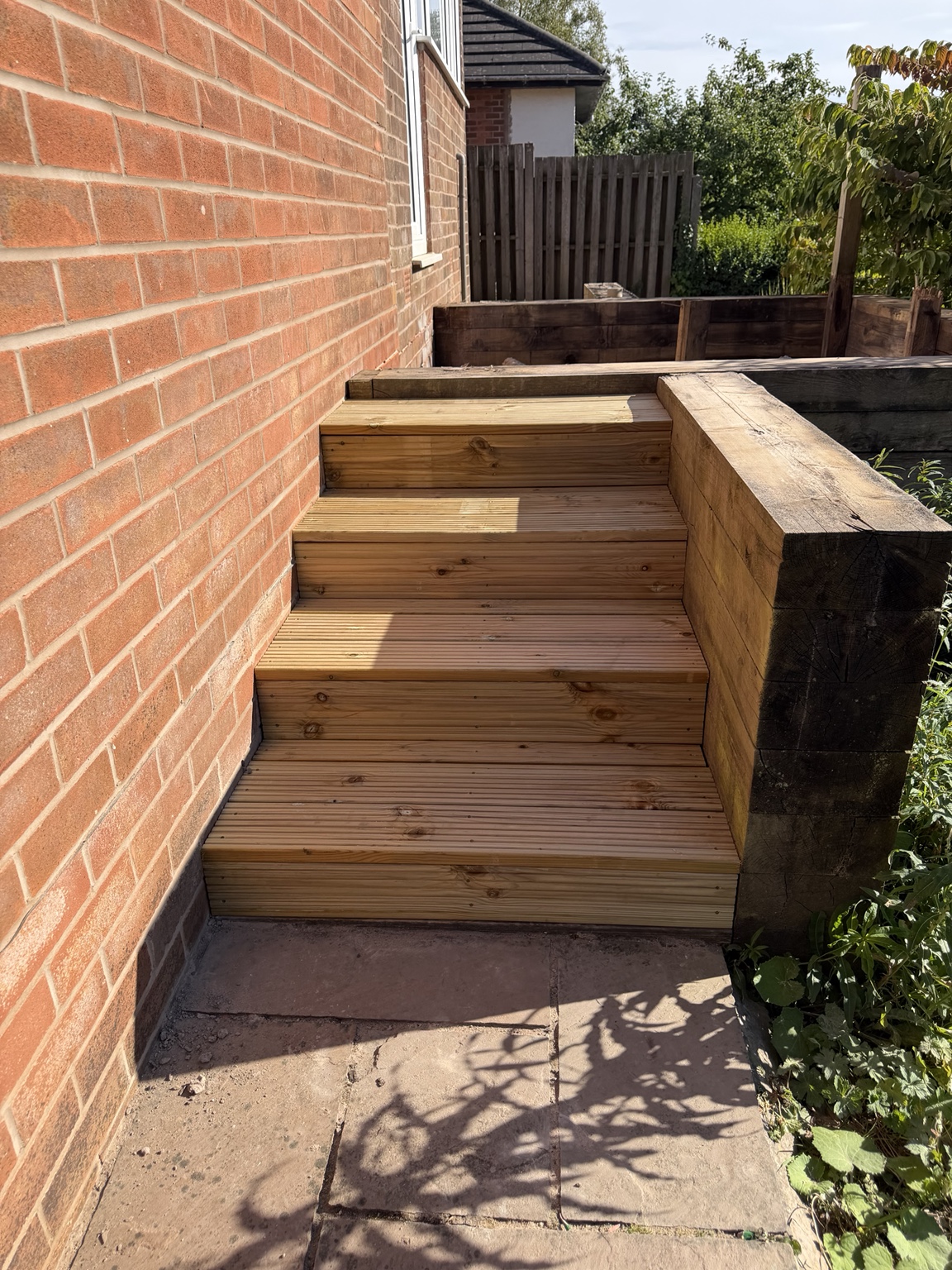Detailed timber decking and steps beside a brick house
